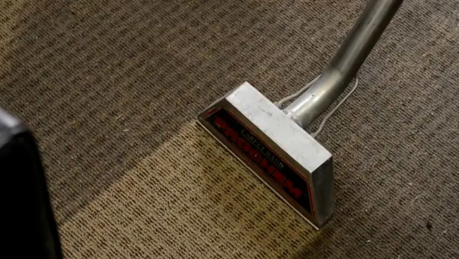 Technician extracting water from wet carpet with professional restoration equipment