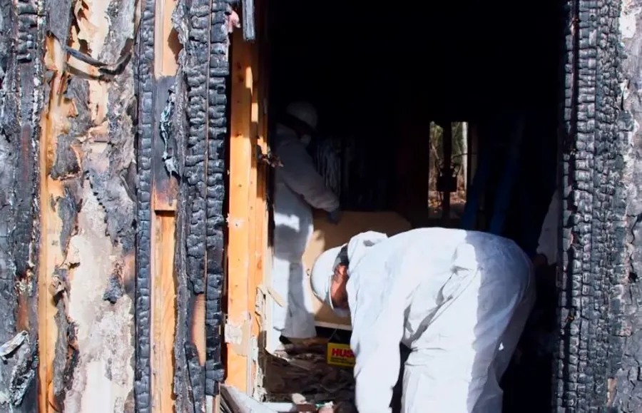 Fire and smoke damage restoration technicians removing debris inside a severely burned property