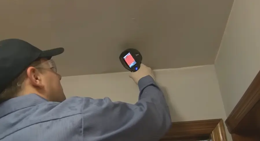 Technician scanning a ceiling with a thermal imaging camera to check for hidden moisture
