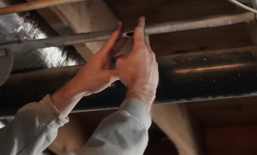 Hands inspecting a damaged pipe under the floor before burst pipe repair Garland